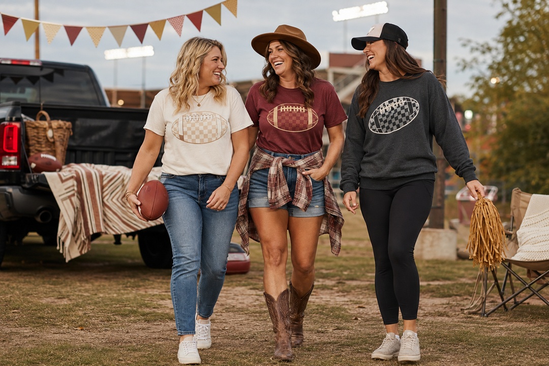 Three women wearing cute football graphic tee outfits at a fall stadium tailgate