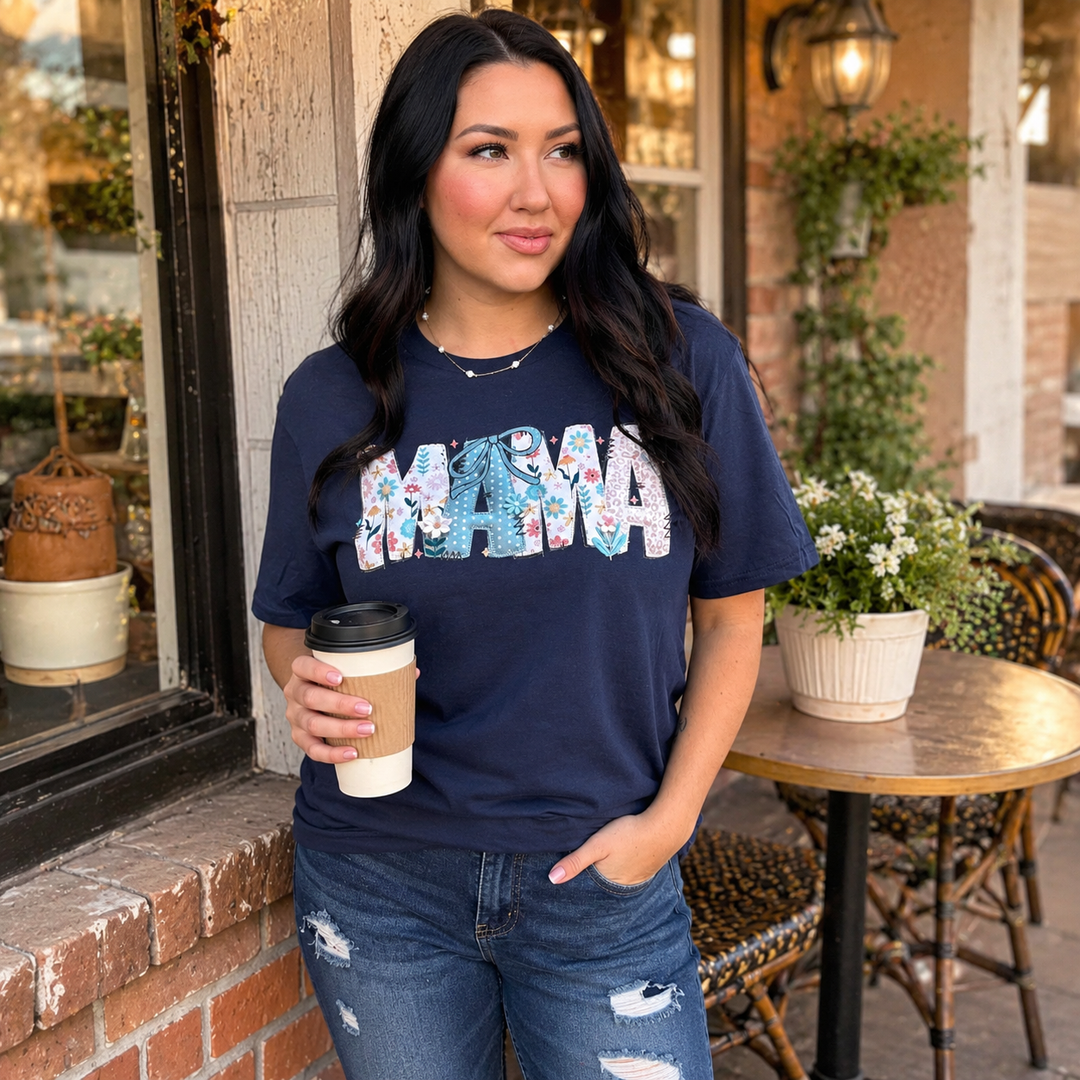 Woman wearing a navy floral MAMA graphic T-shirt on a warm café patio