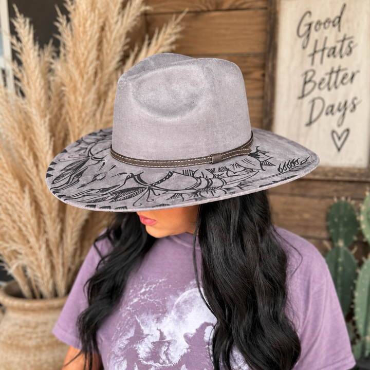 Woman wearing the gray Wildflower Outlaw Western hat with dark illustrated brim and brown band