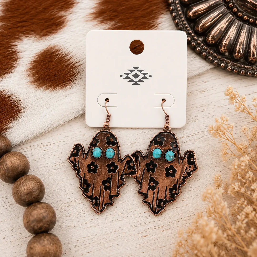 Copper-tone Western ghost dangle earrings with turquoise-colored eyes and black floral details