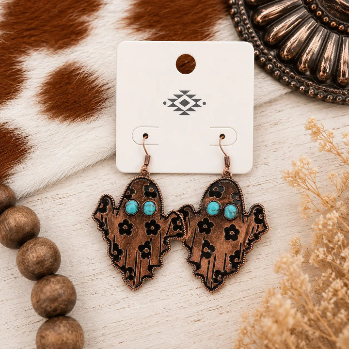 Copper-tone Western ghost dangle earrings with turquoise-colored eyes and black floral details