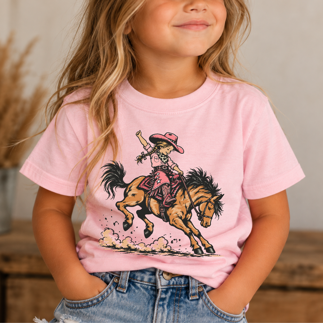 Little Rodeo Girl light pink graphic tee with a vintage cowgirl riding a bucking horse