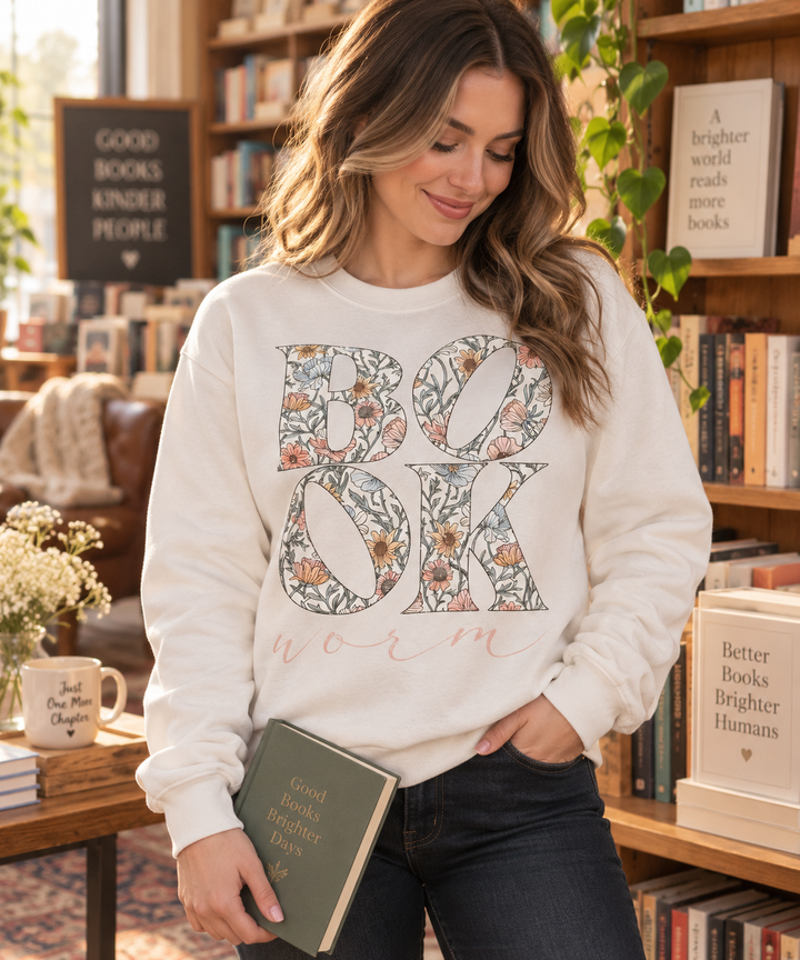 Woman wearing Book Worm floral beige reading crewneck sweatshirt in a bookstore