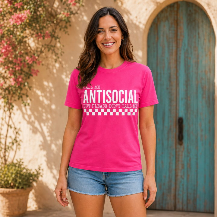 Woman wearing the Call Me Antisocial neon-pink graphic tee by a turquoise Western doorway