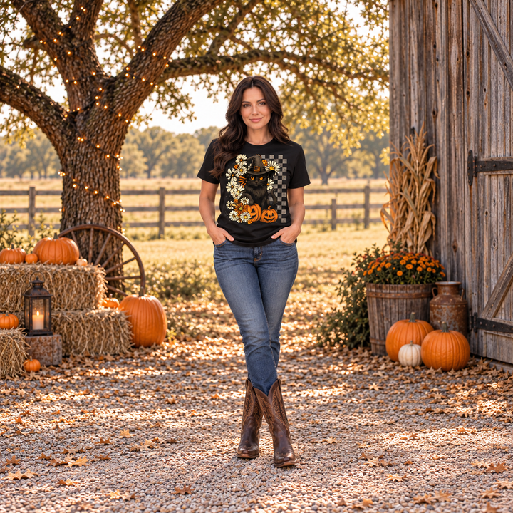Dark-haired woman wearing the Checkered Black Cat Halloween graphic tee by a Central Texas barn