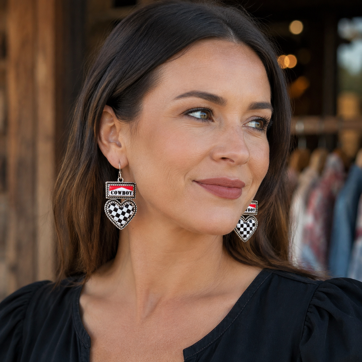 Woman wearing red COWBOY plaque and black and white checkered heart western earrings