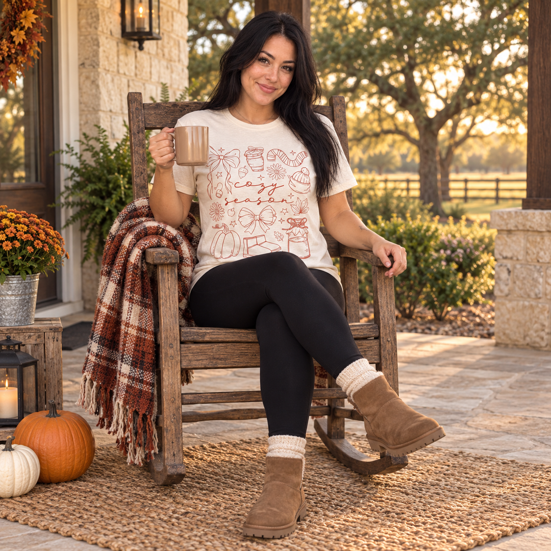 Woman wearing Cozy Season Essentials Natural Fall Graphic Tee on a Texas ranch porch