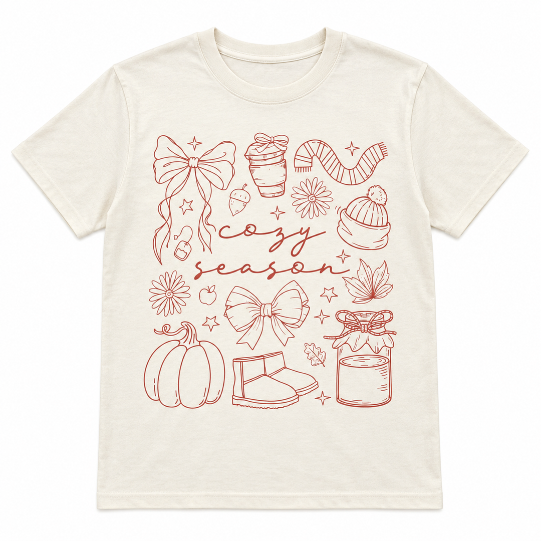 Cozy Season Essentials Natural Fall Graphic Tee laid flat on pure white