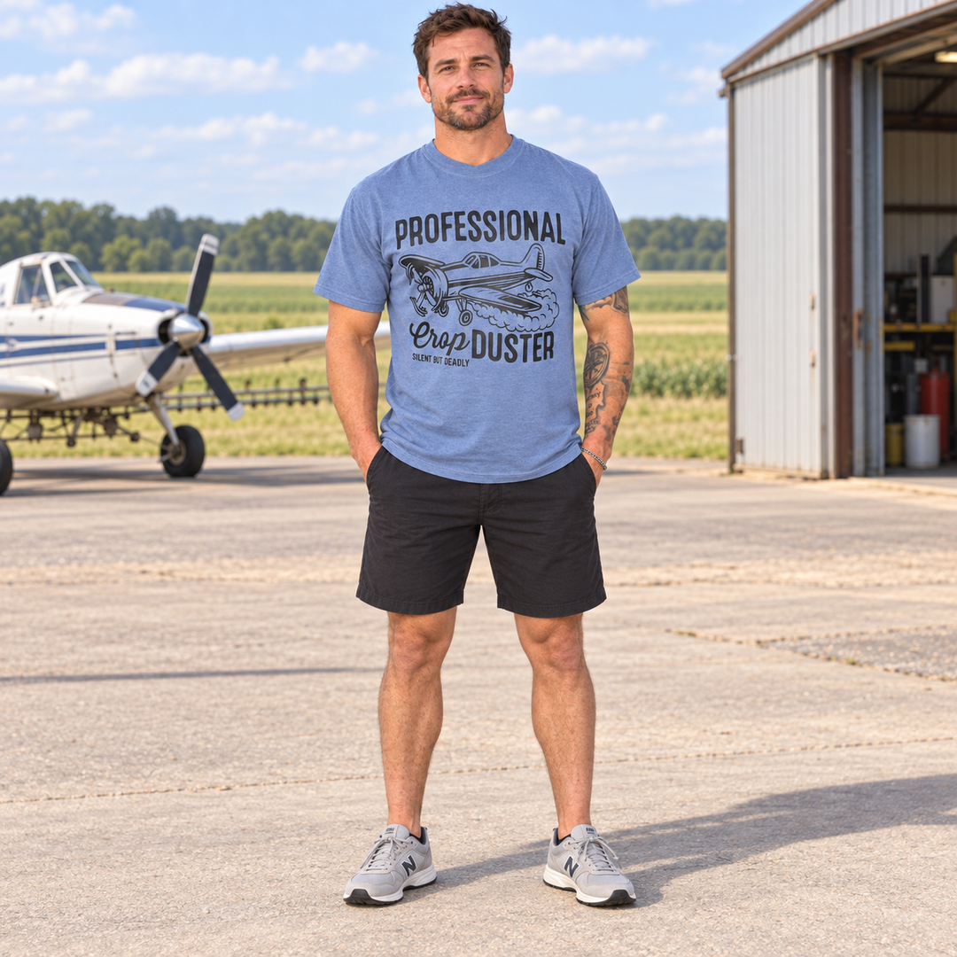 Full-length man wearing Professional Crop Duster Ice Blue funny graphic T-shirt at a Southern rural airfield