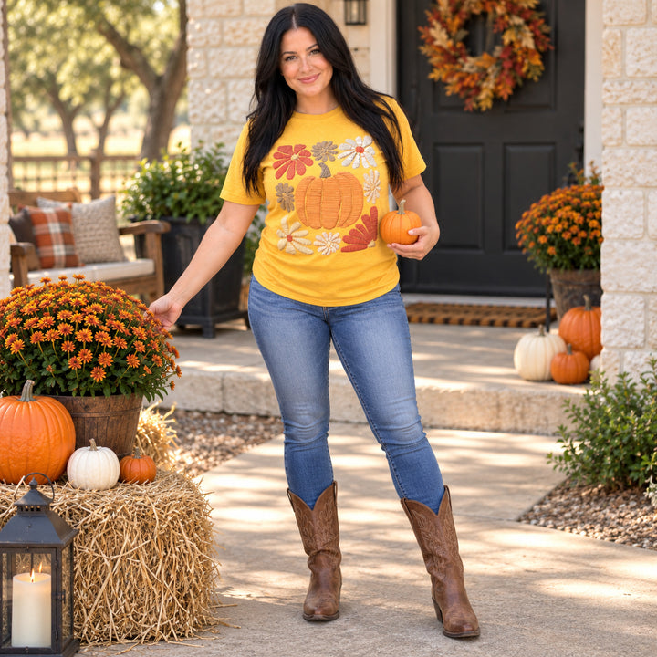 Woman wearing Daisy Pumpkin Mustard Fall Graphic Tee in a Texas fall porch setting