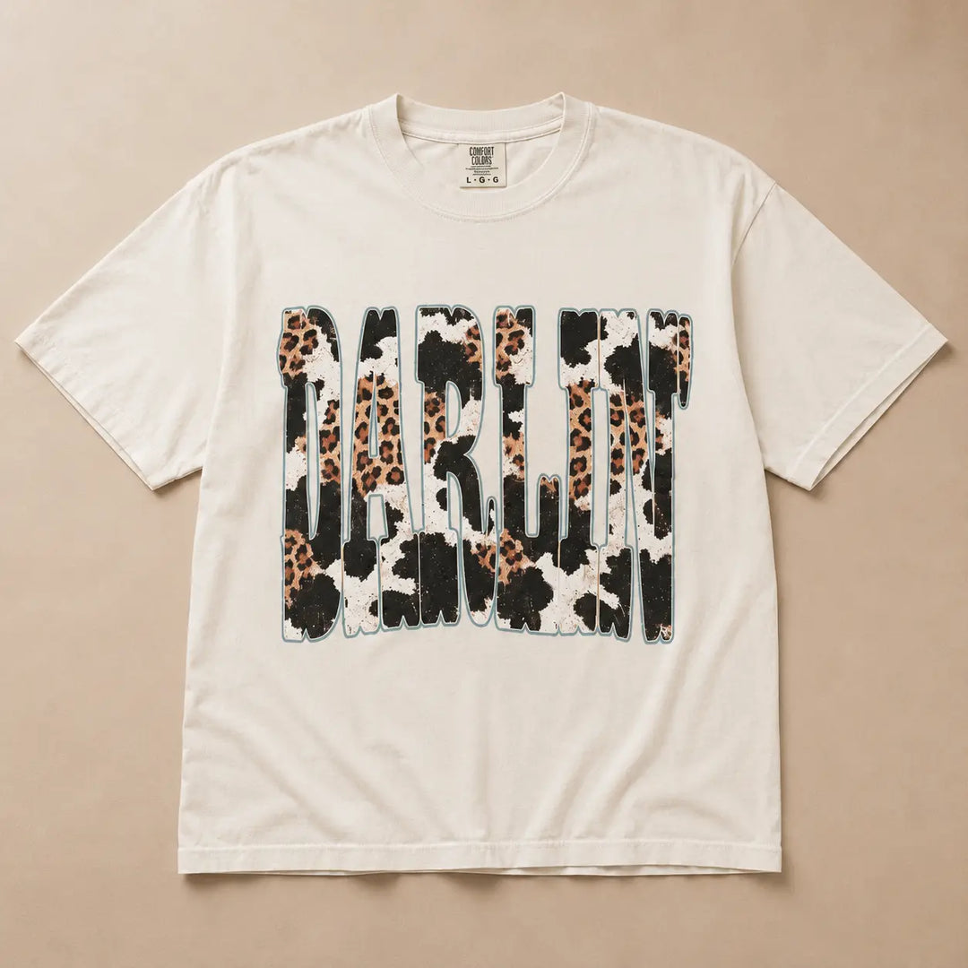 Ivory Darlin graphic tee with leopard, cow print, and turquoise details, flat product view