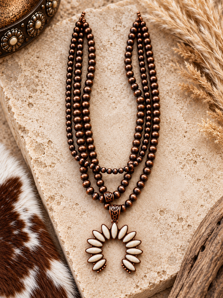 Close styled view of Desert Ivory Squash Blossom Necklace with bronze-tone beads and ivory horseshoe pendant