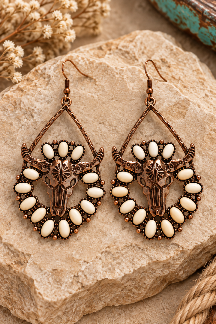 Close styled view of Desert Longhorn Earrings with bronze-tone skulls and ivory oval accents