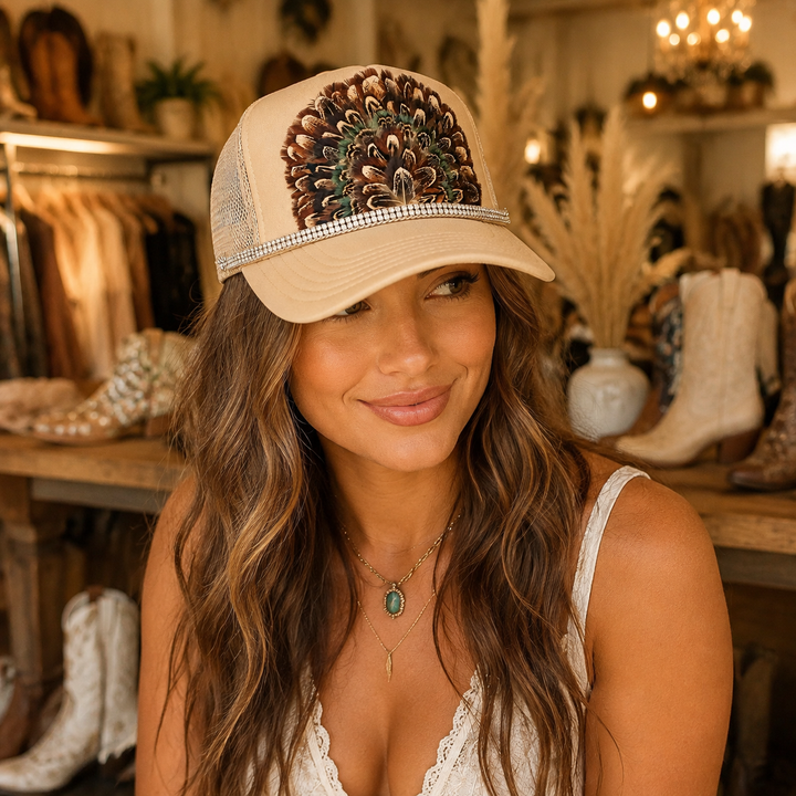 Woman wearing a fitted cream boho trucker hat with feather fan and rhinestone band