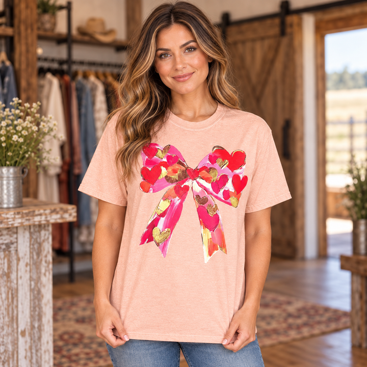 Woman wearing the peach Heart and Bow Valentine graphic tee in a close-up Western boutique portrait