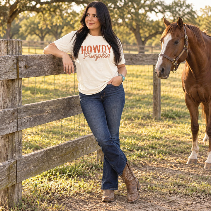 Woman wearing Howdy Pumpkin Rope Natural Western Fall Tee beside a horse on a Texas ranch