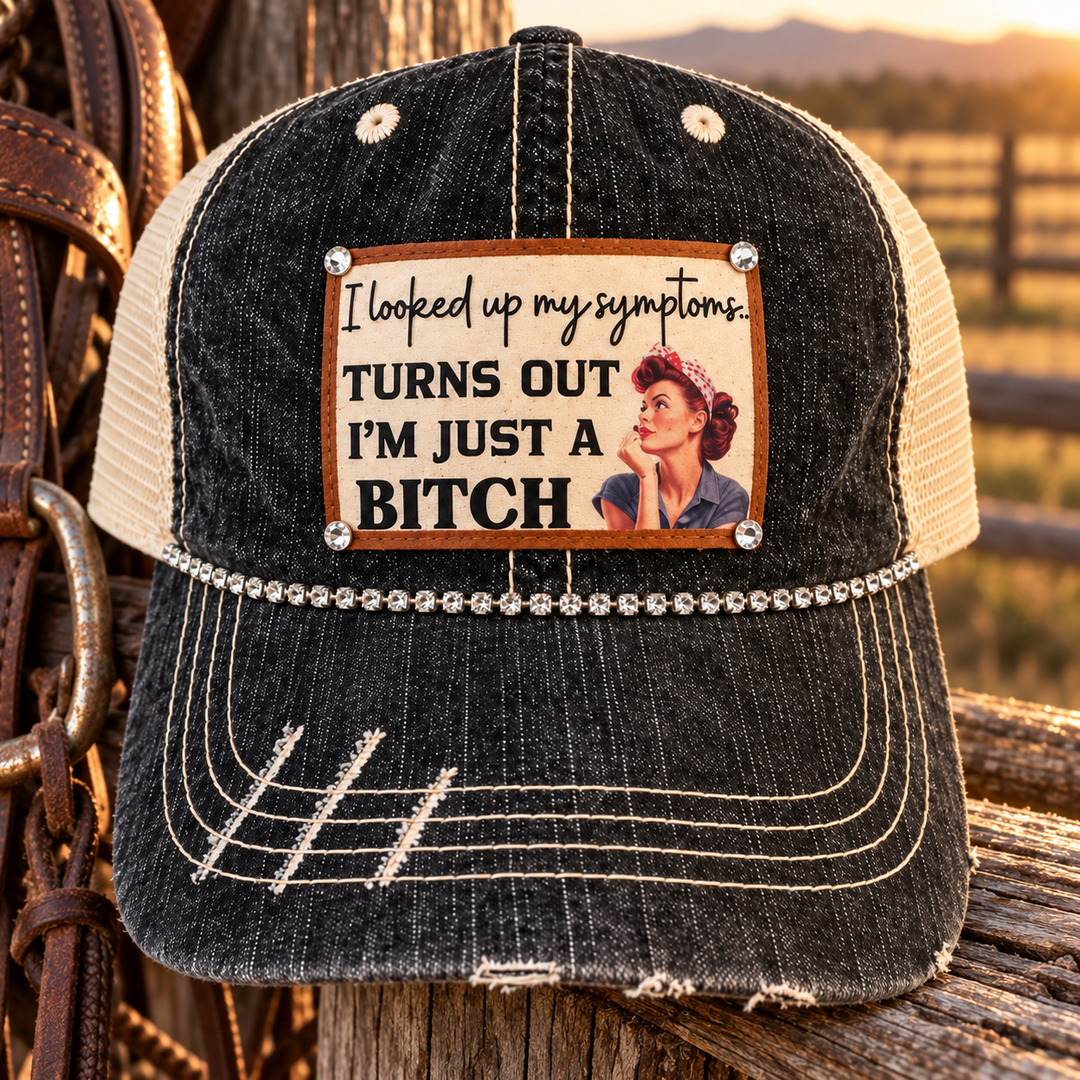 Just a B*tch Trucker Hat styled on a weathered ranch fence with Western leather tack