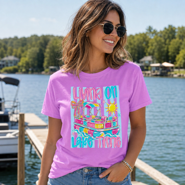 Woman wearing the Living on Lake Time neon violet pontoon boat graphic tee at a lakeside dock