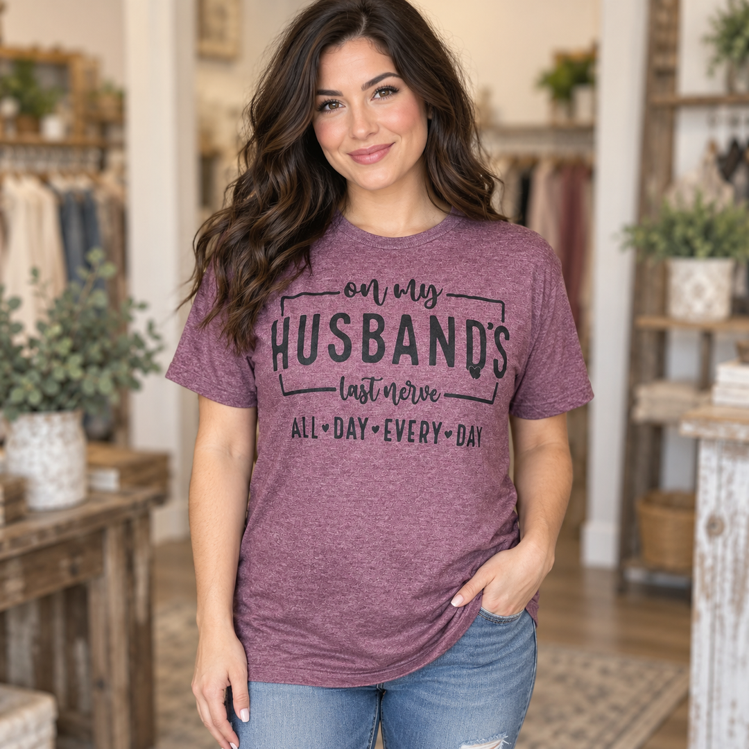 Brunette wearing the burgundy Husband’s Last Nerve graphic tee in a close Western portrait