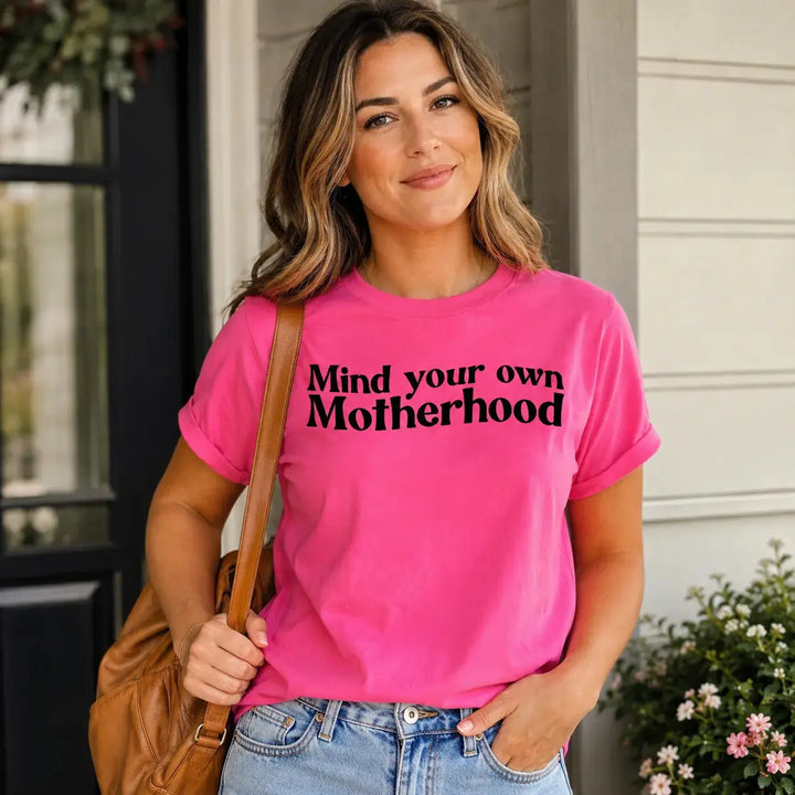 Woman wearing the Mind Your Own Motherhood bright pink graphic tee