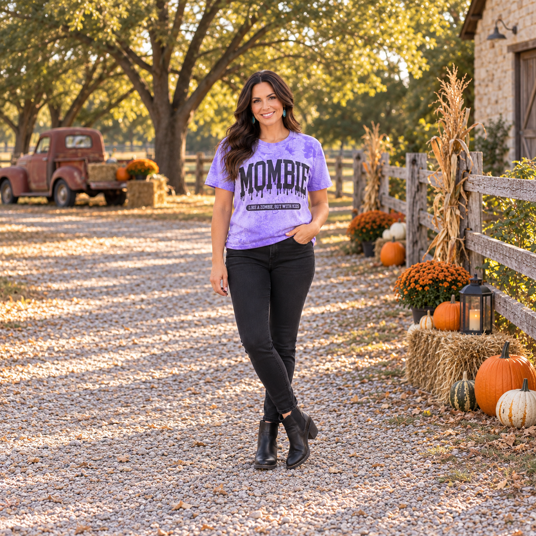 Woman wearing Mombie purple acid-wash graphic tee on a Central Texas fall ranch road