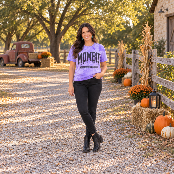 Woman wearing Mombie purple acid-wash graphic tee on a Central Texas fall ranch road