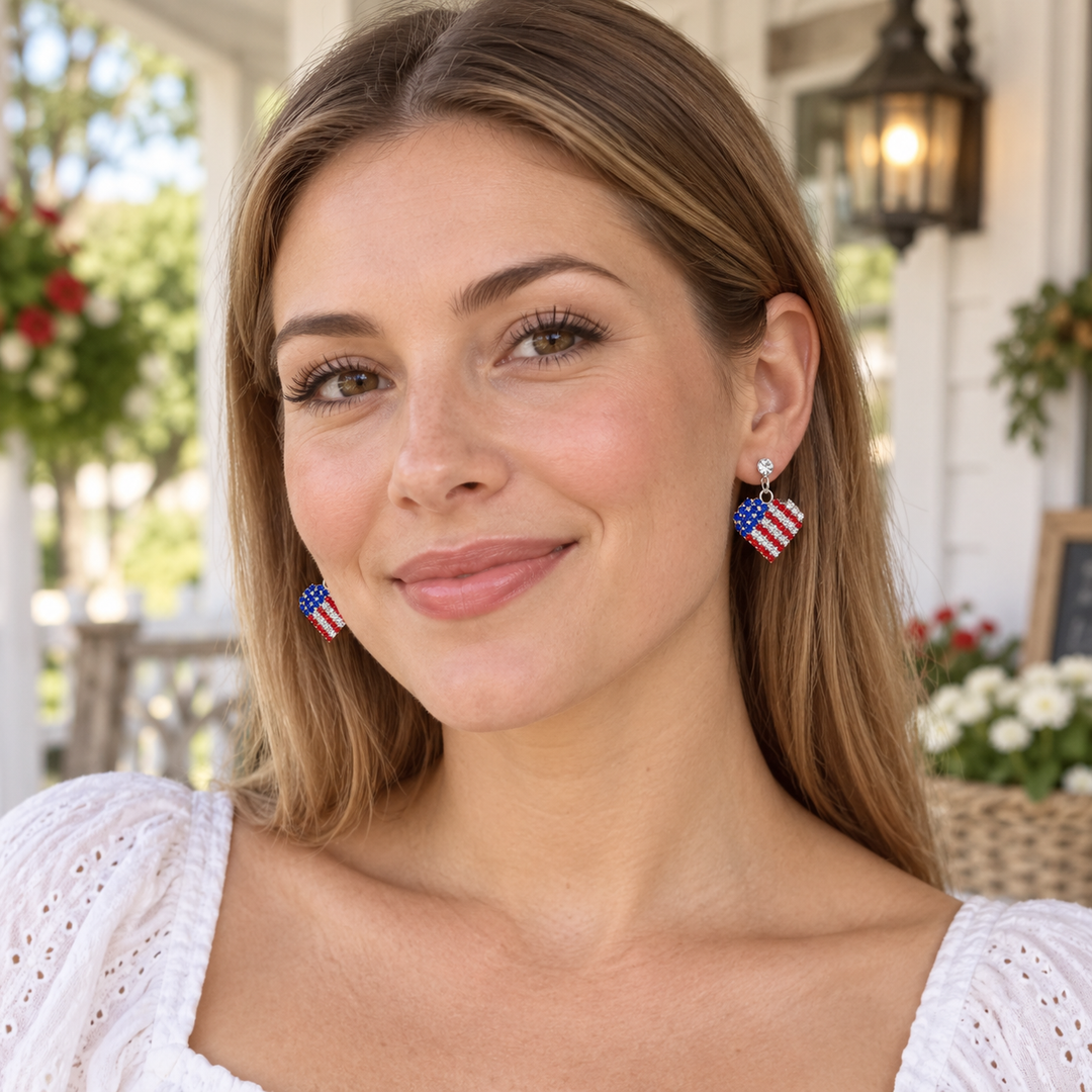 Woman wearing rhinestone patriotic heart dangle earrings