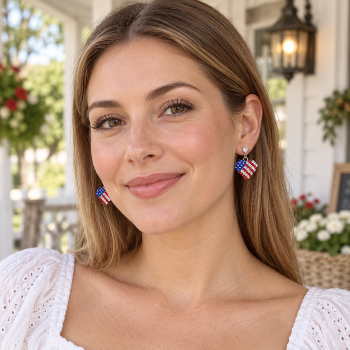 Woman wearing rhinestone patriotic heart dangle earrings
