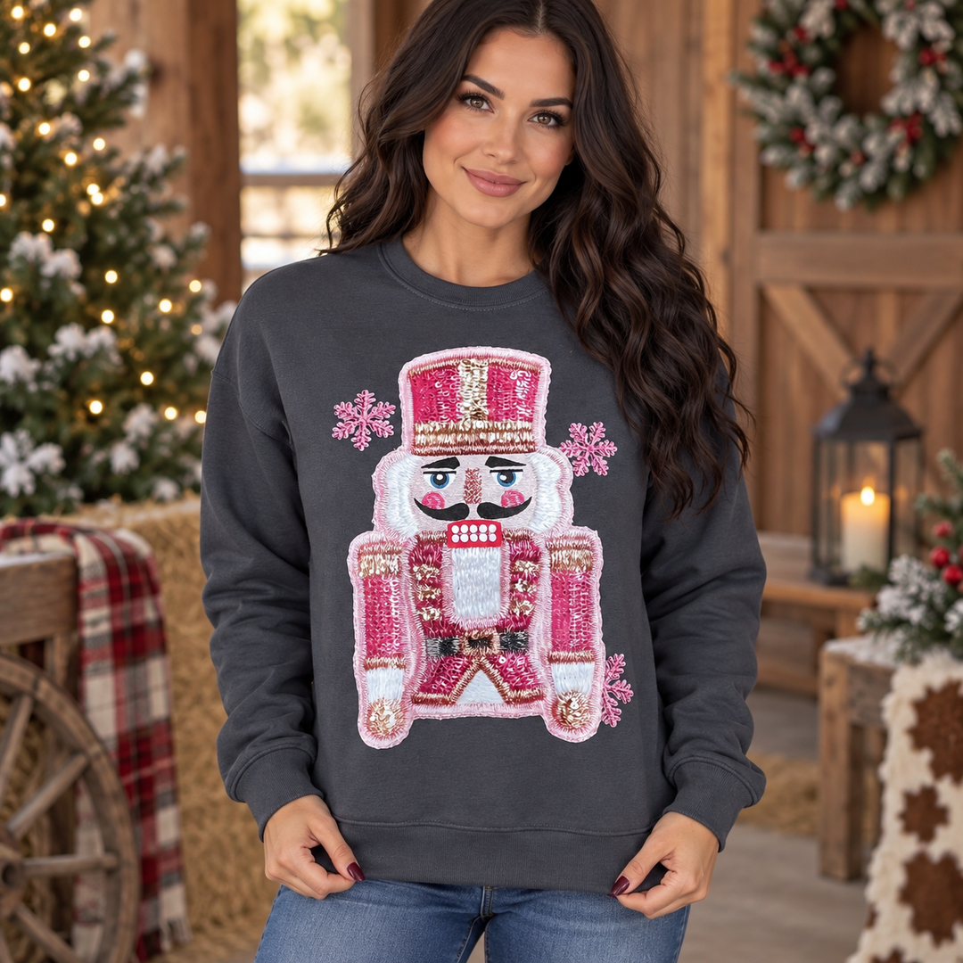 Brunette wearing the charcoal pink faux-stitched nutcracker crewneck in a close Western Christmas portrait