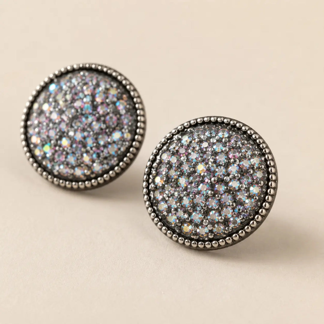 Close detail of silver-tone round stud earrings filled with iridescent rhinestones