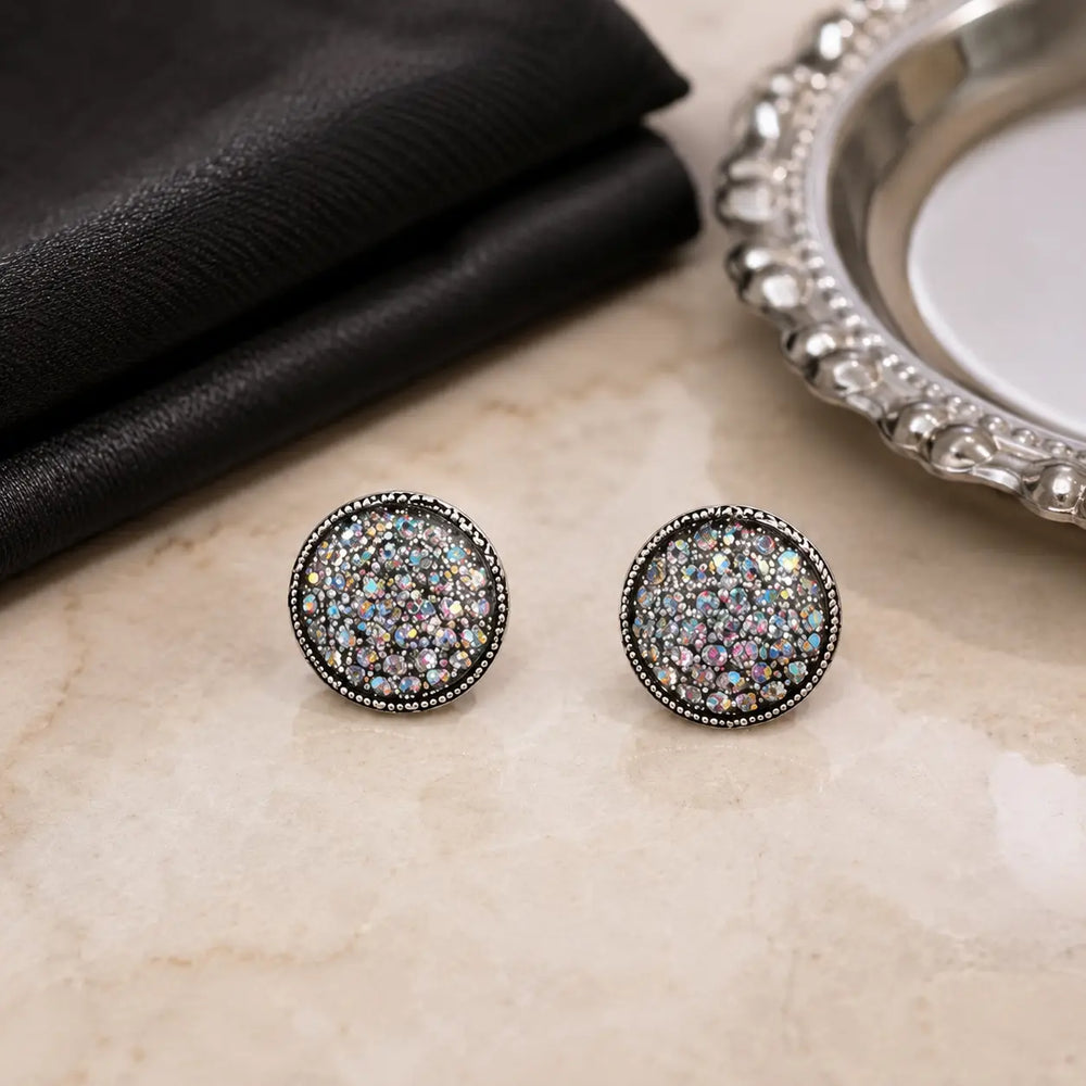 Rhinestone circle stud earrings styled with black fabric on a softly lit vanity