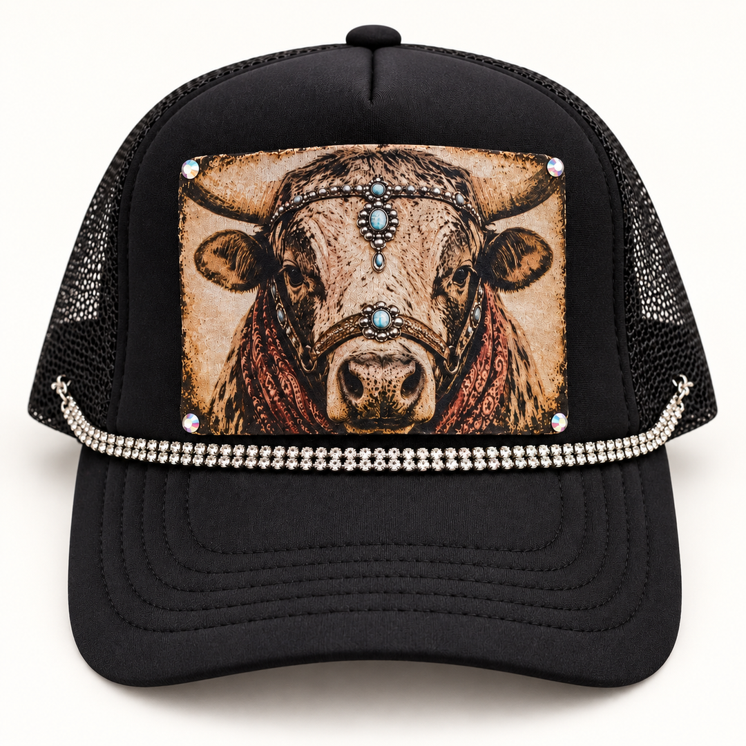 Lay-flat view of Rhinestone Ranch Cow Trucker Hat with black crown, vintage cow patch, turquoise and rust details, and rhinestone trim