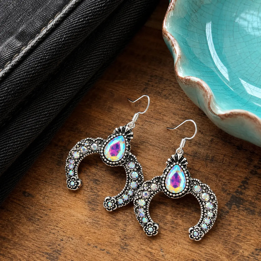 Rhinestone squash blossom dangle earrings styled beside black denim and a turquoise-colored dish