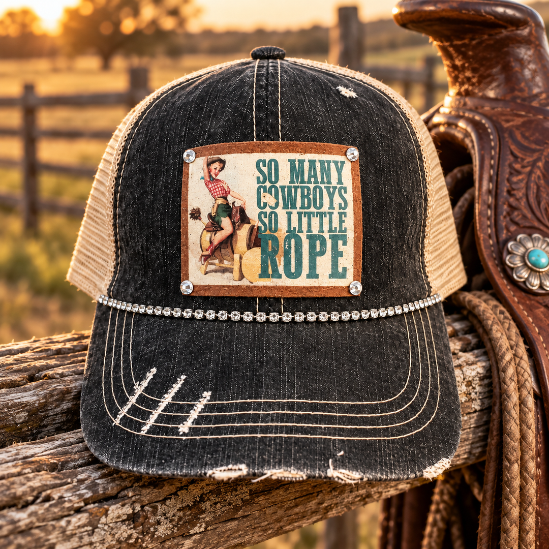 So Many Cowboys Trucker Hat styled on a rustic ranch fence beside a leather saddle
