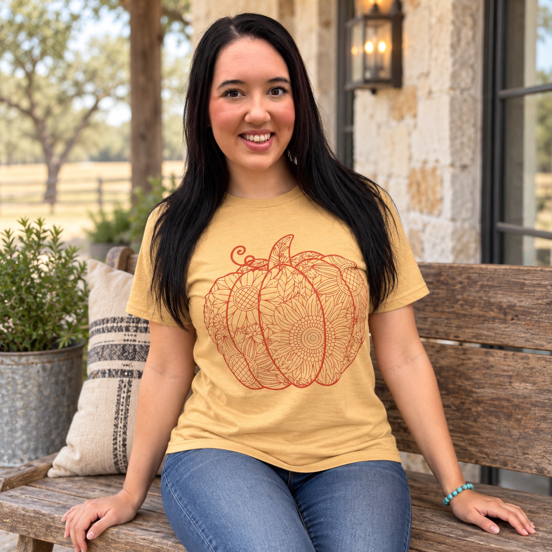 Woman wearing Sunflower Pumpkin Cutout Old Gold fall graphic tee on a ranch porch