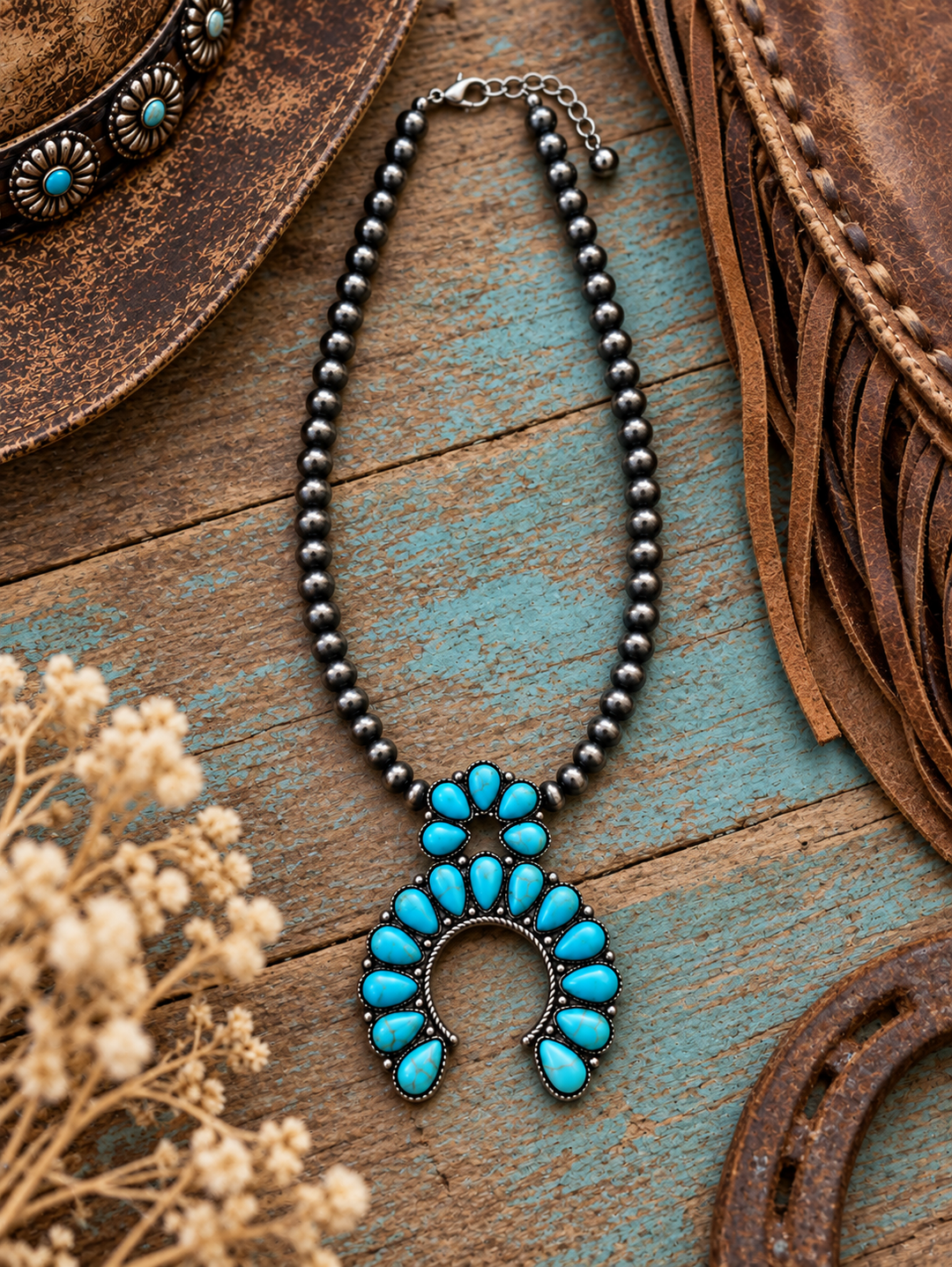 Turquoise Blossom Squash Necklace styled on weathered turquoise wood with Western leather