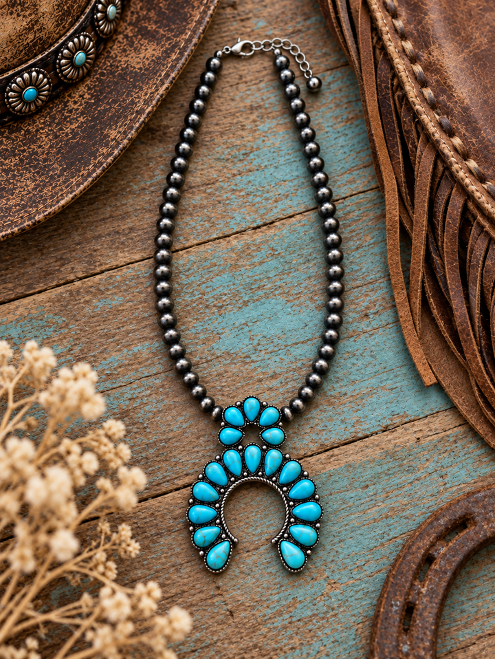 Turquoise Blossom Squash Necklace styled on weathered turquoise wood with Western leather