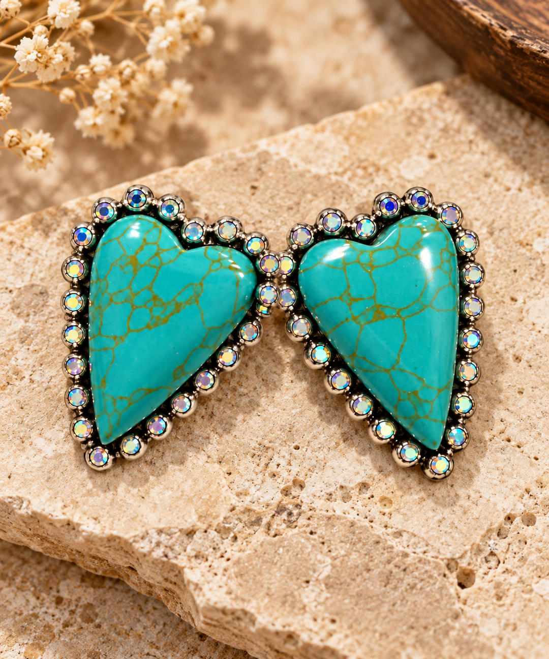Close styled view of Turquoise Heartbreaker Earrings with turquoise heart stones and sparkling silver-tone borders