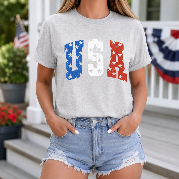 Woman wearing the USA Stars patriotic ash-gray graphic tee on a decorated summer porch