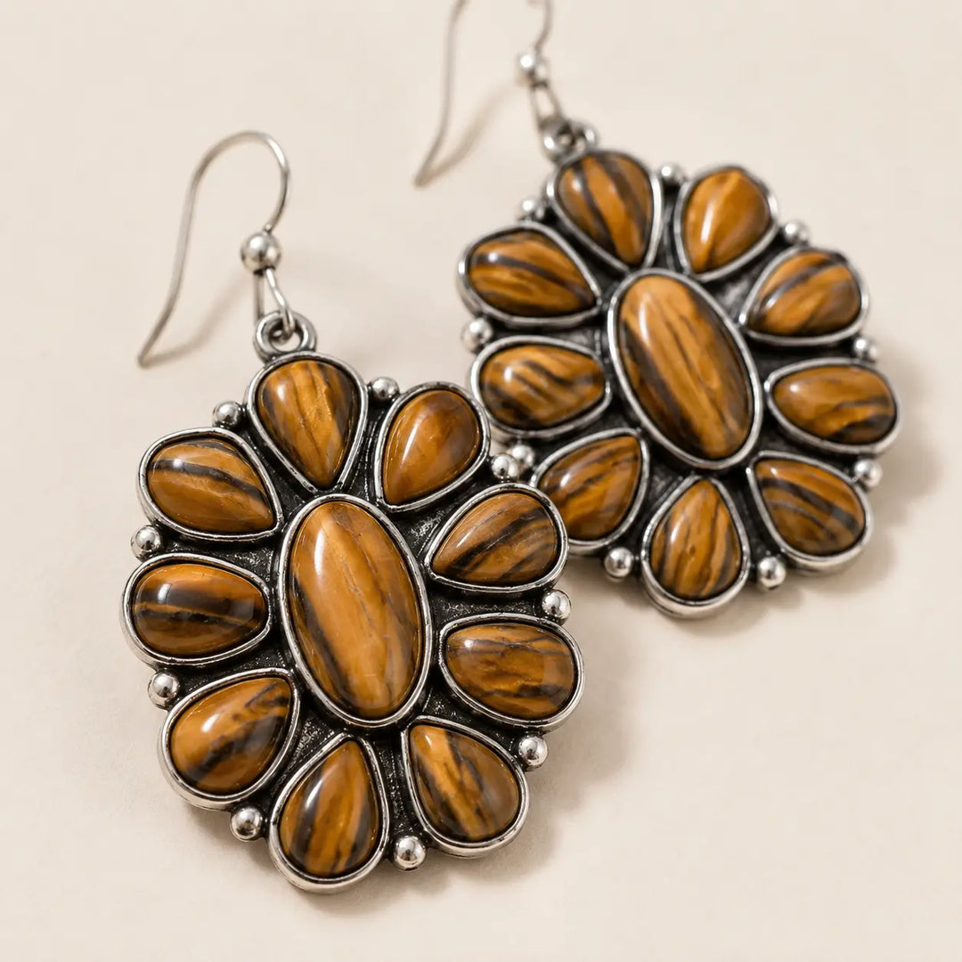 Close detail of silver-tone woodgrain concho dangle earrings with brown accents